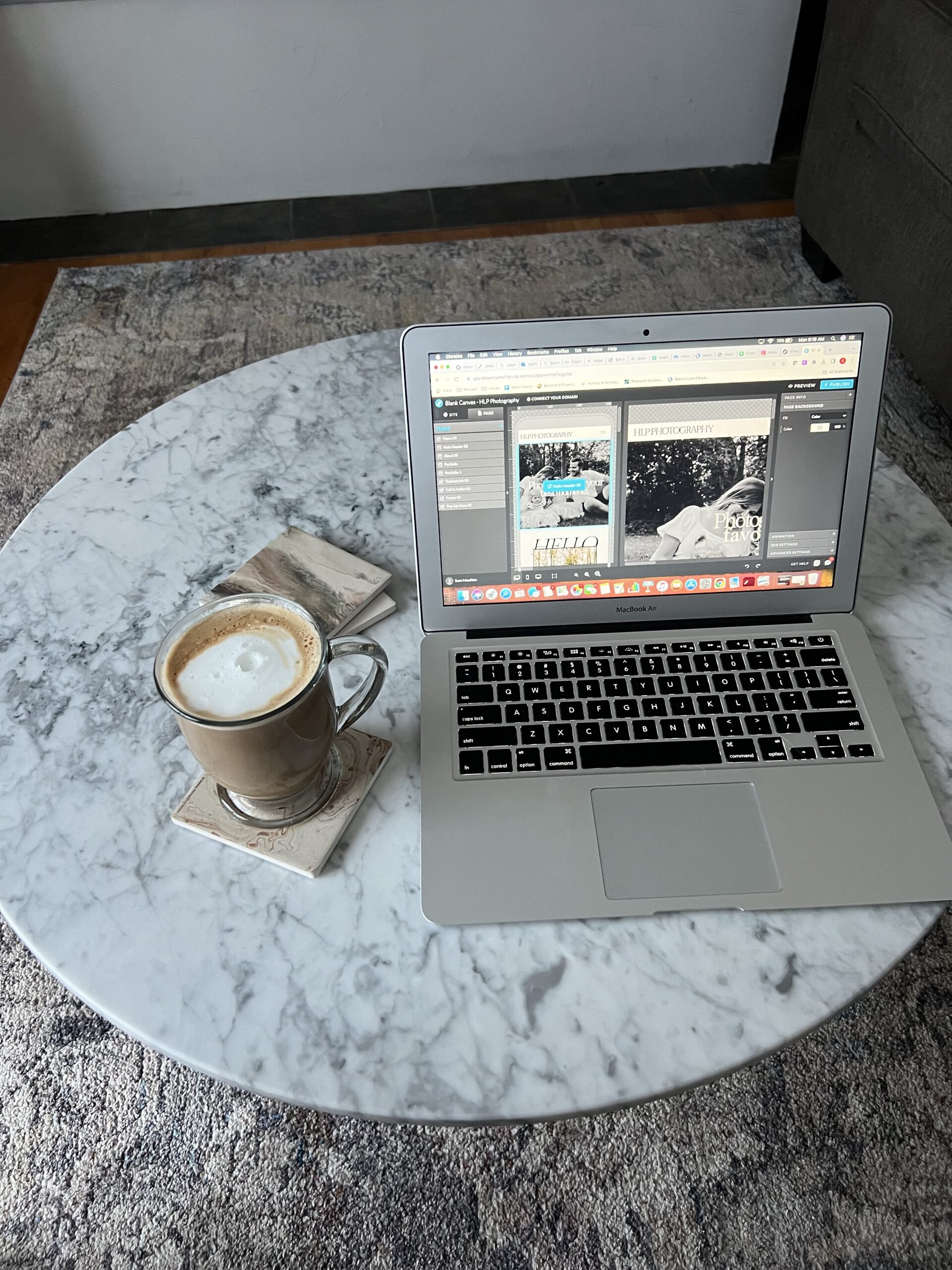 Female entrepreneur working on Showit website design on MacBook with coffee on marble table