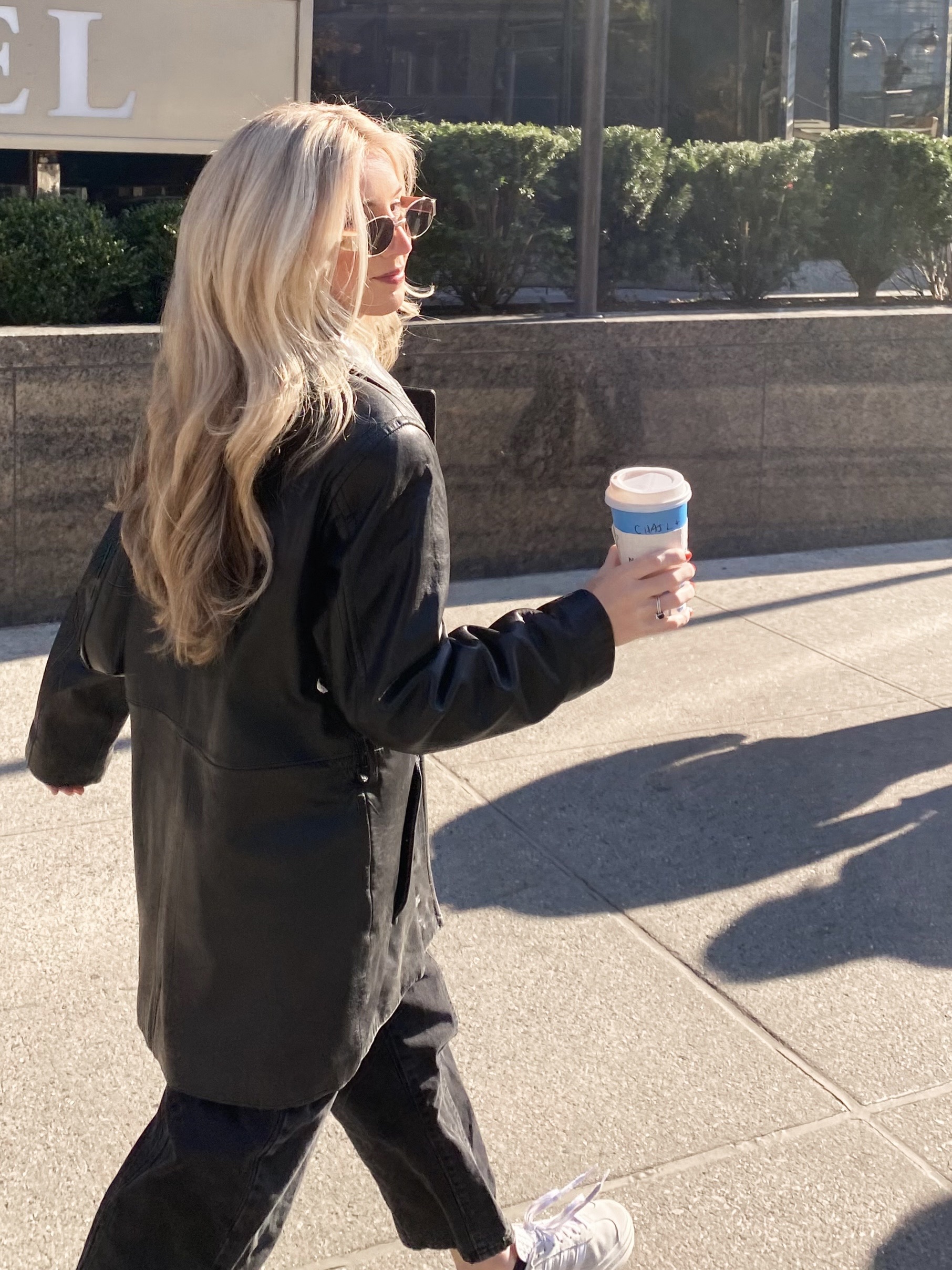 Business coach walking with coffee cup reviewing website conversion checklist on mobile device